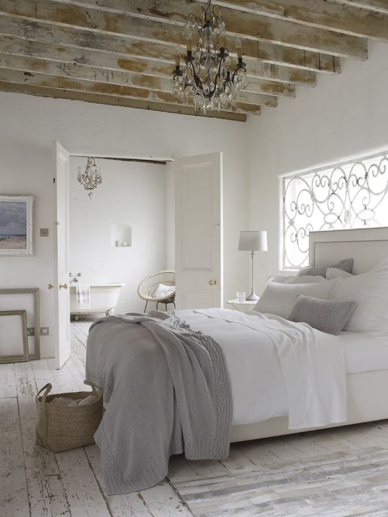 a modern white upholstered bed, rustic and shabby wooden beams and floors