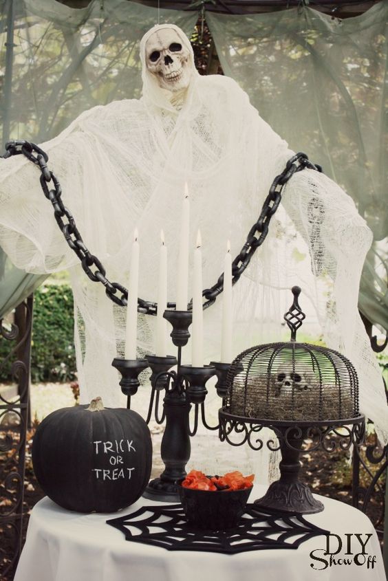 a stunning Halloween display of a cheesecloth ghost with a skull, a black pumpkin and a skull display