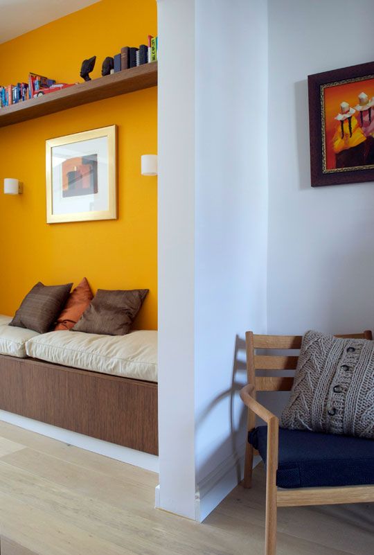 a statement wall in bold yellow helps to divide the living room and the entryway visually