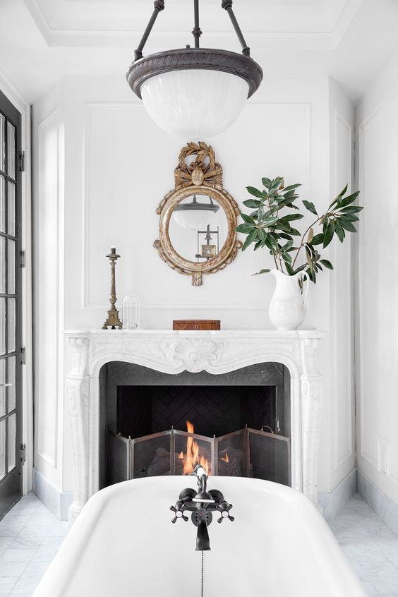 a vintage fireplace in the bathroom is working, there's a metal screen and burning firewood
