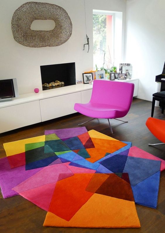 a colorful geo rug and a hot pink chair for a modern cheerful living room