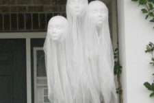 22 floating head hanging ghosts over the porch are made of tulle and doll heads