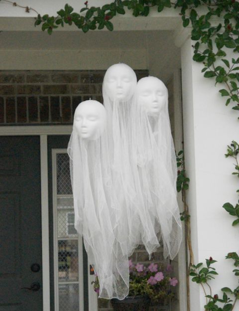 floating head hanging ghosts over the porch are made of tulle and doll heads