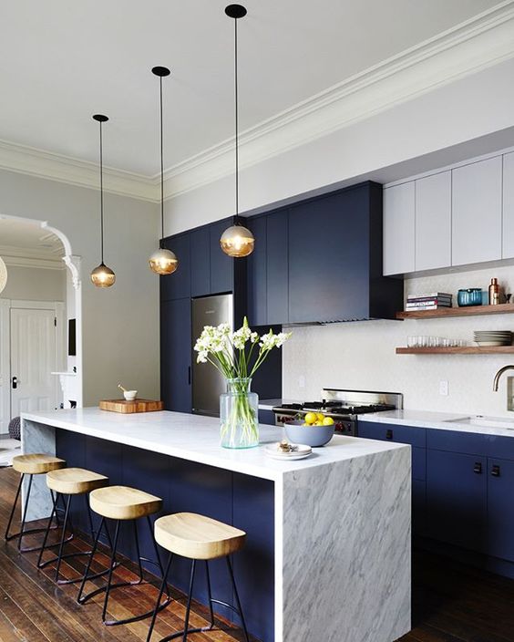a kitchen island with a marble top acts as a cooking and eating space to save the space