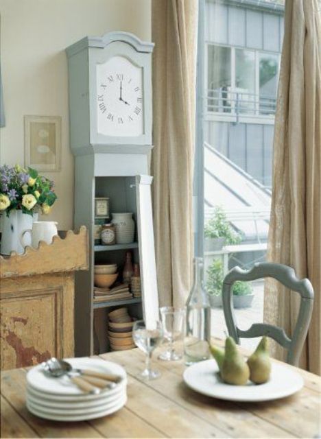 a light blue grandfather's clock is used as a dinnerware storage piece and a clock