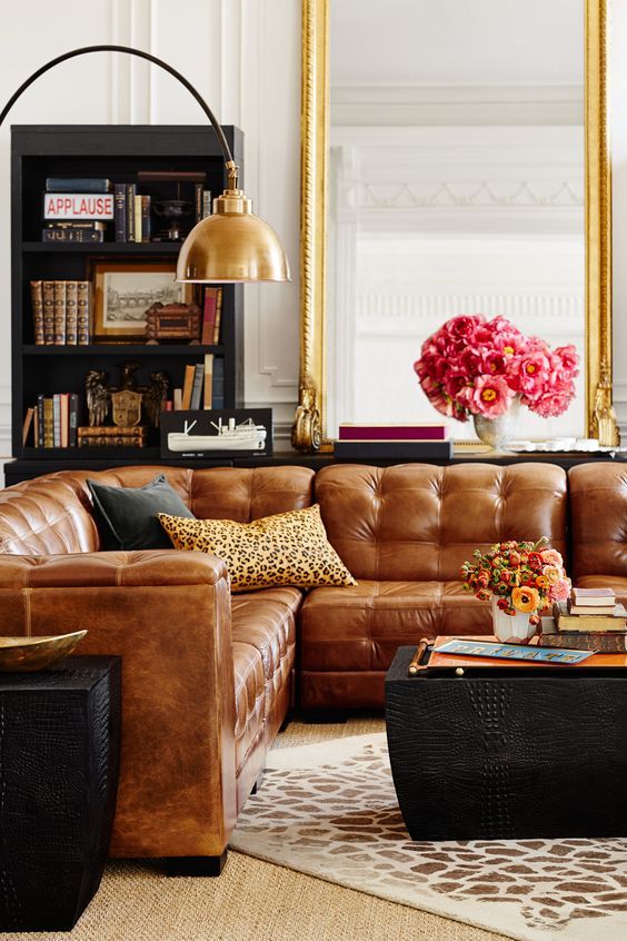 a luxurious brown leather sofa is accentuated with a cheetah print pillow and black leather side tables