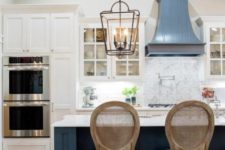 24 a dark blue kitchen island stands out in the white kitchen cabinets