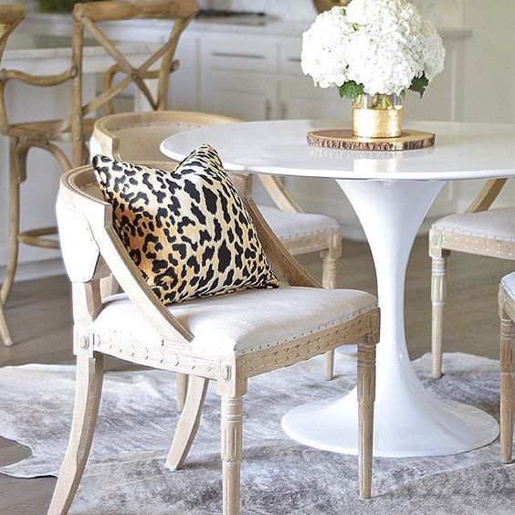 a neutral and chic dining space with a cheetah print pillow and a cow skin rug
