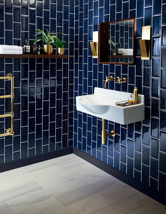 glossy navy tiles clad vertically for a bold art deco bathroom, chic brass touches