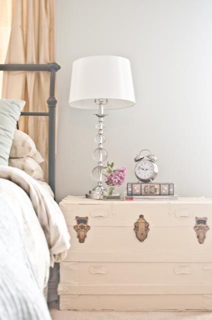 a whitewashed wooden trunk as a refined bedside table for a feminine bedroom