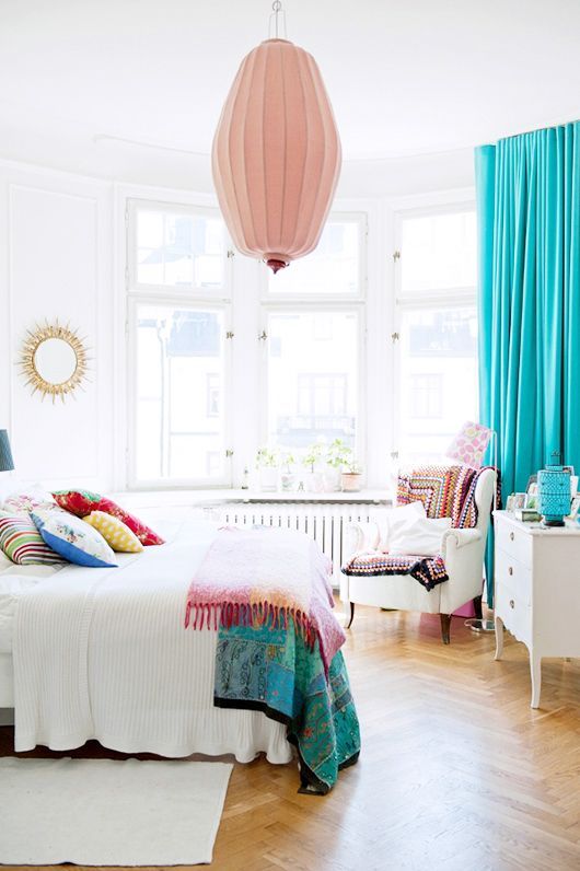 turquoise curtains and bedspreads and pillows add cheer to this white bedroom