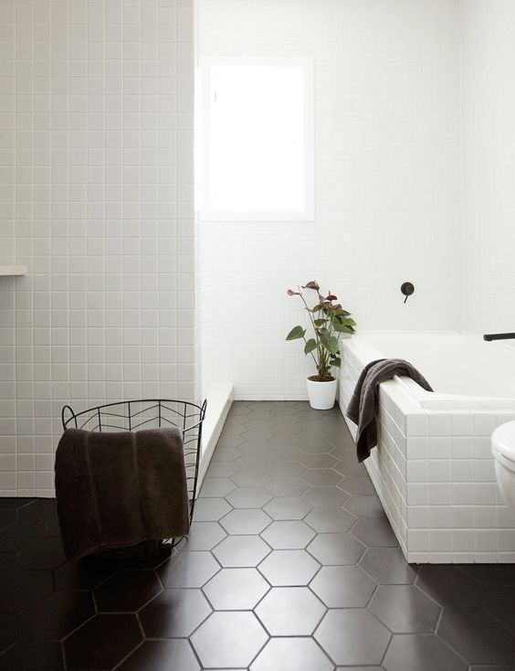 Small white square tiles and matte black hex ones create a chic Scandinavian inspired space