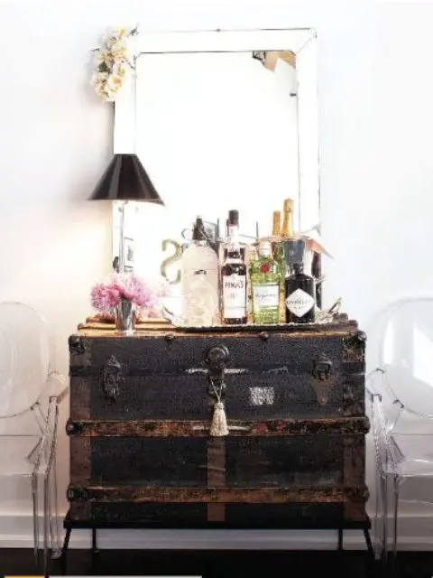 a large black vintage chest is used as a home bar, and everything necessary is inside it