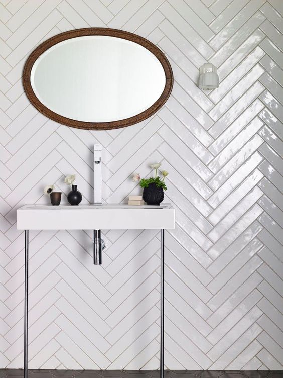 Glossy white tiles clad in a herringbone pattern to make the bathroom more eye catching