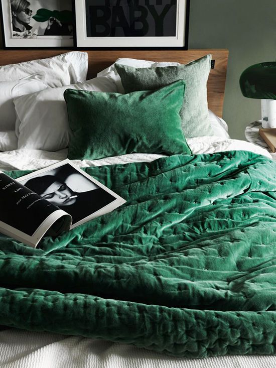 an emerald bedspread and pillow helps to follow the velvet trend and makes the bed inviting