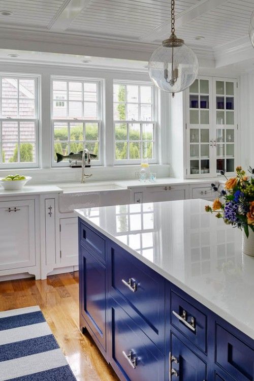 a white kitchen with an electric blue island that hints on its seaside theme