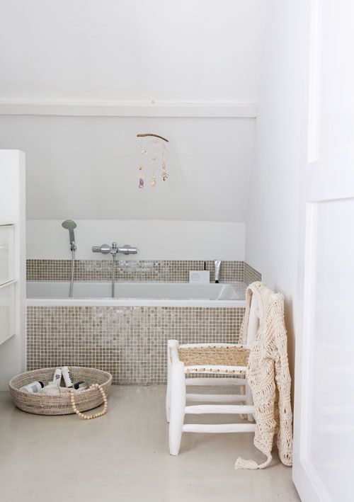 tiny glossy beige tiles civer the bathtub and the zone around it attracting attention