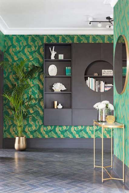The entryway of this quirky penthouse is done with bold emerald anad gold wallpaper and lots of gilded details
