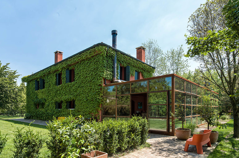 This Italian country house was covered with living vines to make it look very natural and it got an additional glass volume that merges with the surroundings