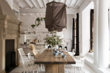 03 The dining space features a wooden table and some simple white chairs, an antique hearth and fabric-covered lamps