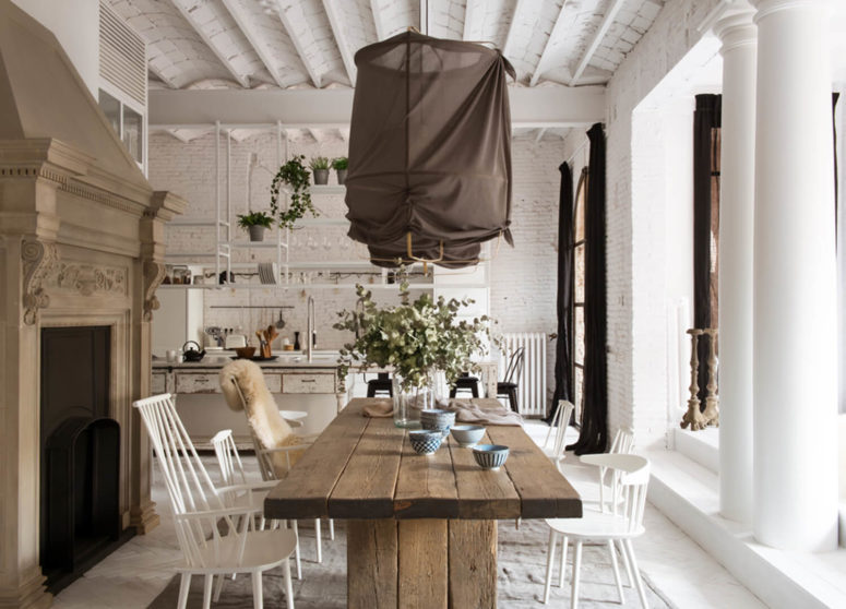 The dining space features a wooden table and some simple white chairs, an antique hearth and fabric-covered lamps