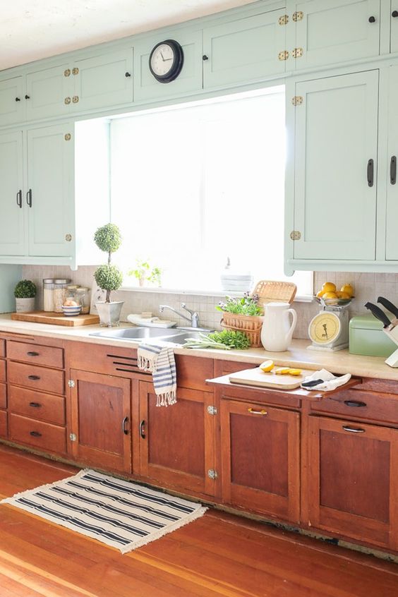 a farmhouse kitchen with neutral wall cabinets and burnt orange ones on the floor