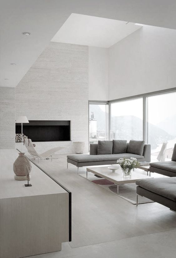 a neutral space with a textural fireplace wall, large windows and comfy grey furniture