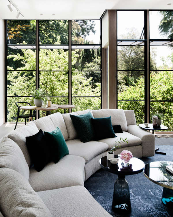 The living room features a framed glazed wall, a large rounded sofa, a breakfast zone