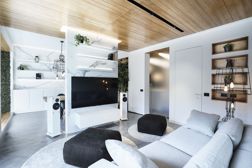 The living room is light colored, light grey and white, with black touches and open shelving