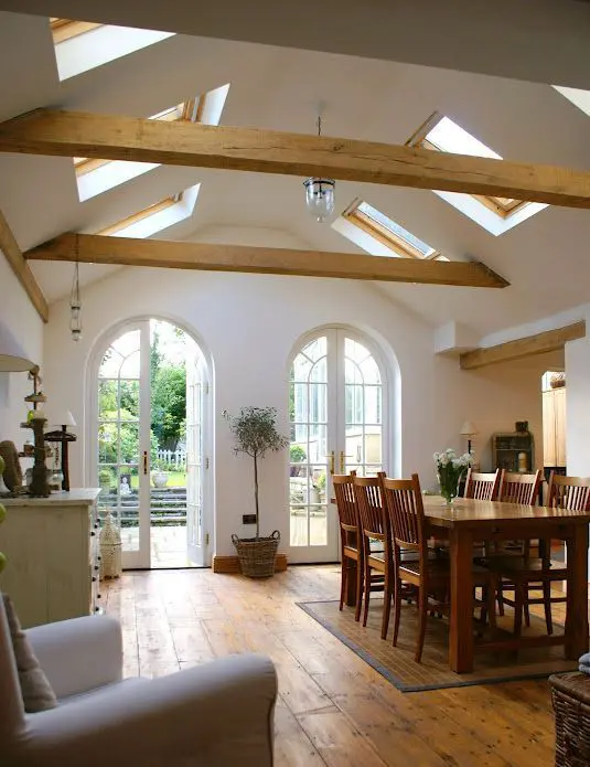 a vaulted ceiling with skylights and wooden beams brings a rustic feel and light in