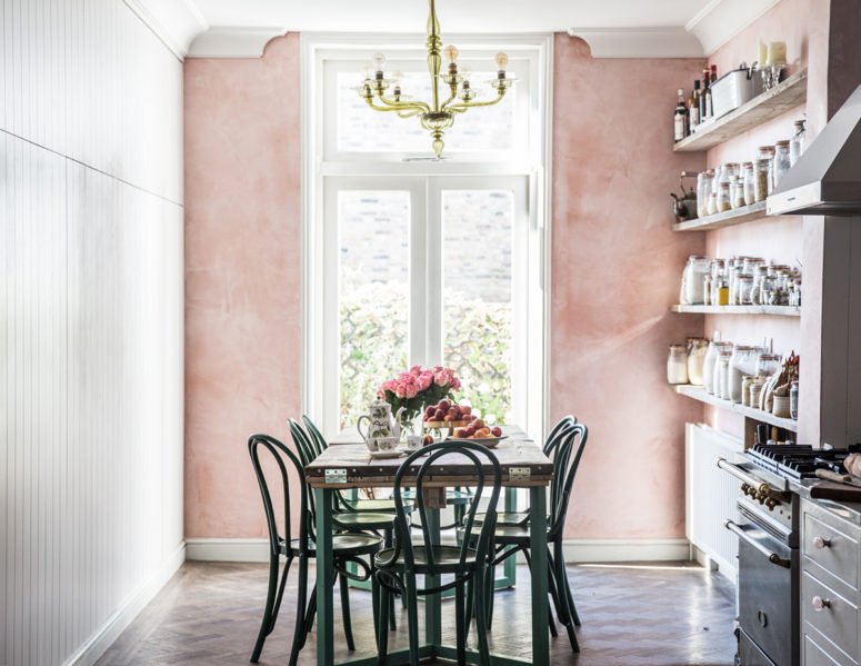 a vintage-inspired kitchen and dining zone with a pink wall looks very cute