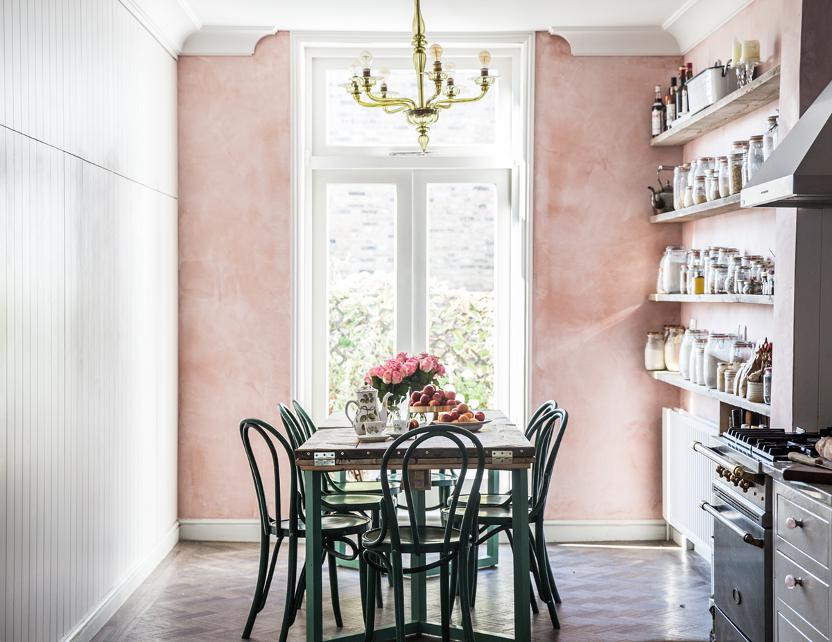 A vintage inspired kitchen and dining zone with a pink wall looks very cute