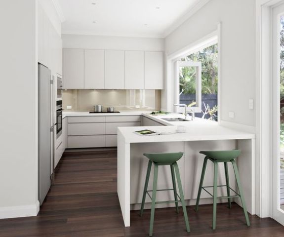 A white U shaped kitchen with a breakfast zone and a large window