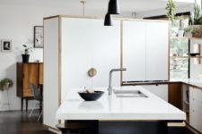 05 The kitchen is done with cool white cabinets with wooden handles, a large kitchen island with a white countertop, which doubles as a breakfast zone