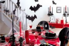05 a bold black and red tablescape with red candles, a red tablecloth, bats around and a black chandelier with spider webs