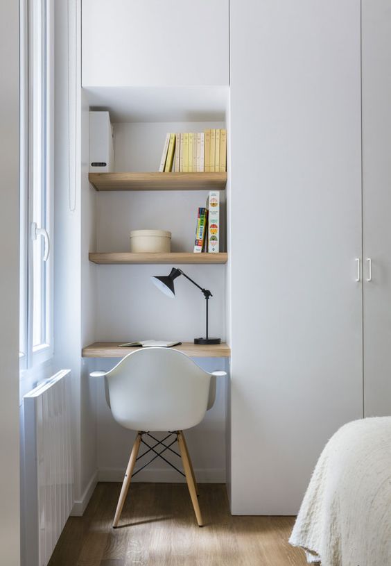a very small and compact working space with built-in shelves by the window