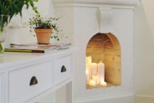 05 a whitewashed non-working fireplace features some candles, which make the space cozier and comfier