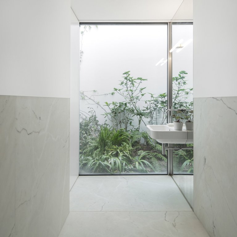 The bathroom is with a view to outdoors, and a tall wall protects the owners from unwanted eyes