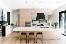 06 The kitchen is done with light-colored wooden cabinets, some marble and black touches