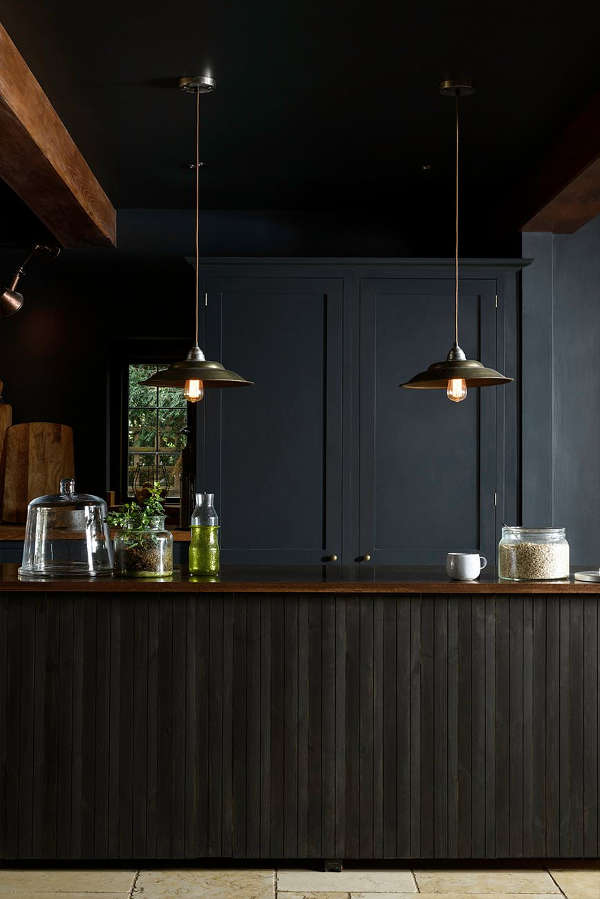 The kitchen island with clad with black wooden planks in a very eye catchy way
