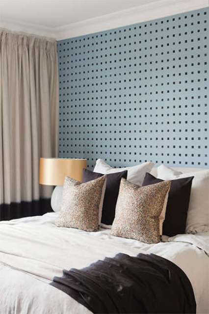 The master bedroom is done with a blue pegboard wall, a large bed and metallic shade lamps