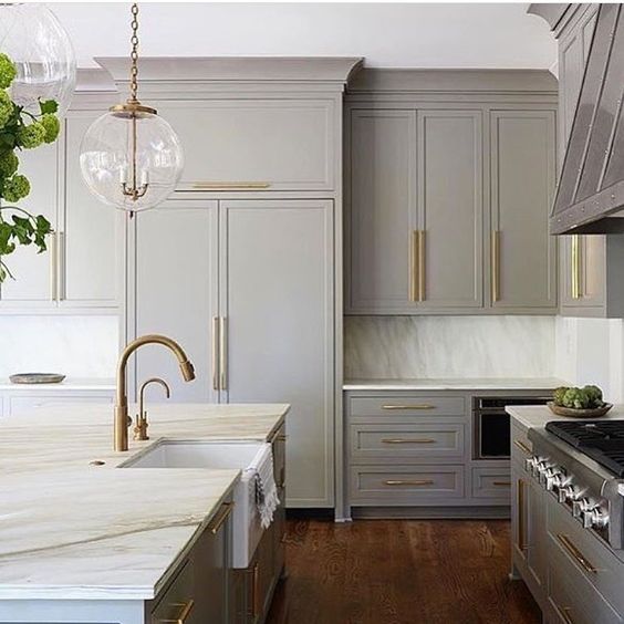 a vintage light grey kitchen with brass touches and antique-styles fixtures looks elegant