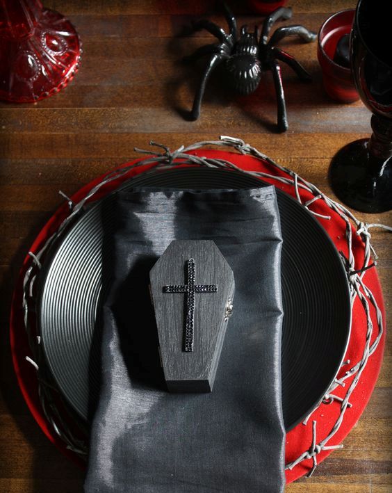 a black and red tablescape with spiders, coffins and textured plates for a vampire party