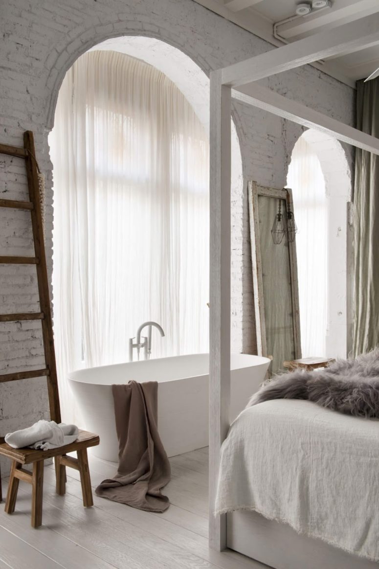 Big arched windows bring much light in, and a bathtub looks chic and gorgeous