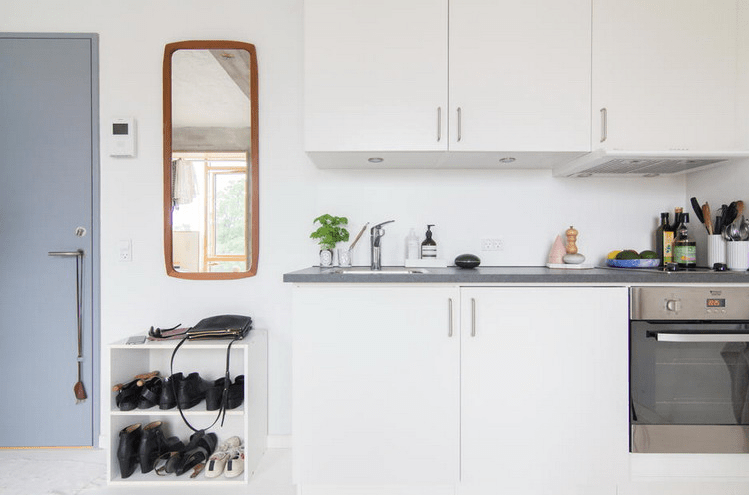 The kitchen is all-white, with grey countertops and it's located at the entrance