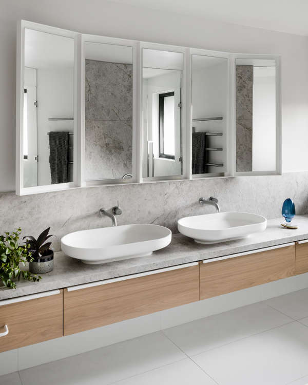 The large master bathroom is done with grey concrete, a large mirror, vanity and two sinks