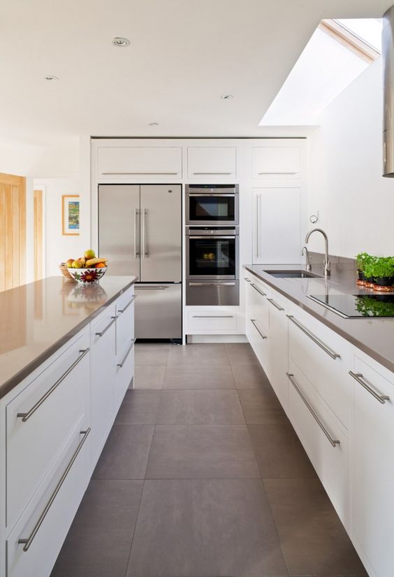 a modern white kitchen with stainless steel counters, handles and appliances