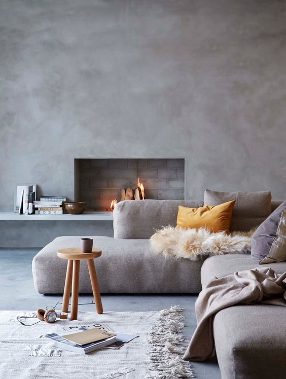 a modern space with concrete walls, a working fireplace, comfy upholstered sofa and textiles