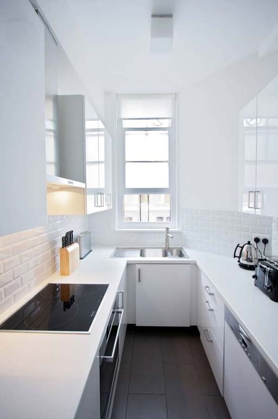 a tiny yet very functional minimalist white kitchen with a U shape