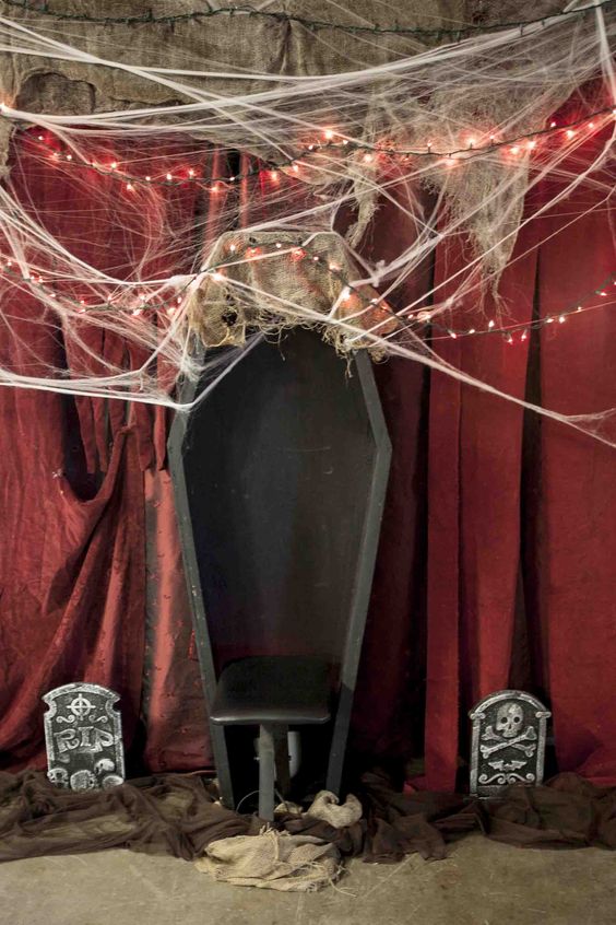 an old open coffin, some cobwebs, red string lights and dollar store tomb stones surrounded by brown tulle